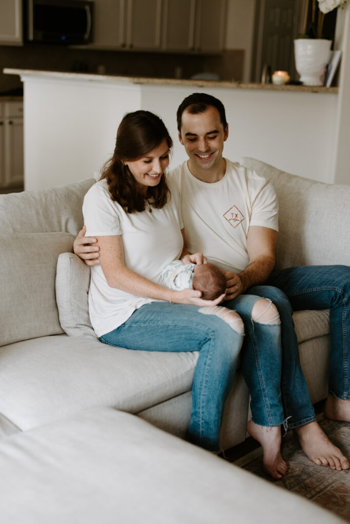 new born baby being held and looked at by smiling parents